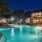 a pool with a fountain in front of a house at night