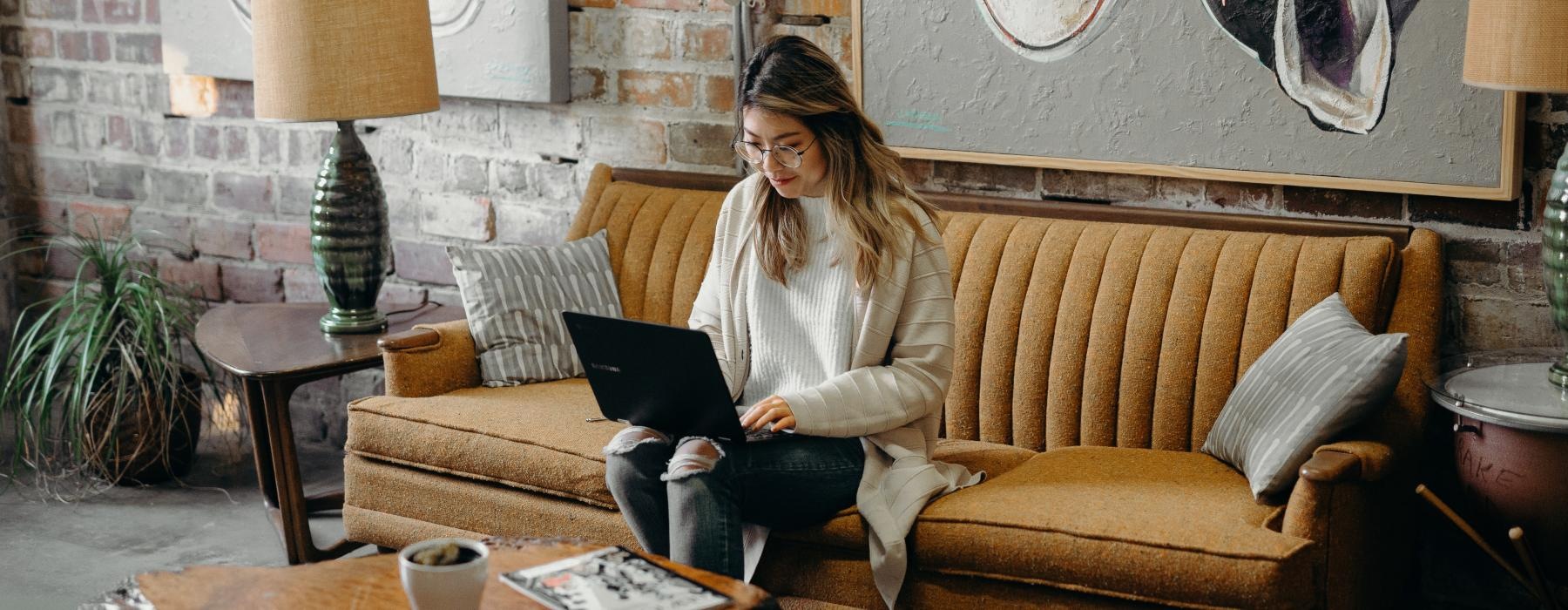 a woman sitting on a couch using a laptop